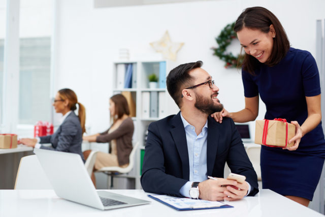 Mann bekommt ein Weihnachtsgeschenk am Arbeitsplatz überreicht