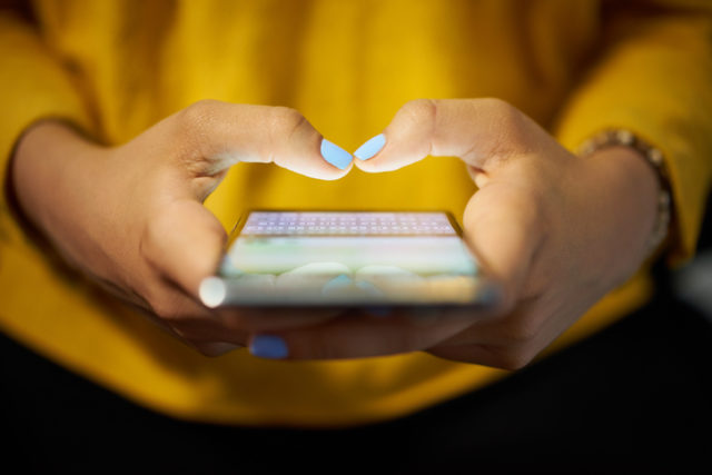 Eine junge Frau tippt eine Nachricht auf ihrem Smartphone