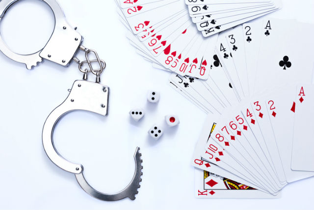 Handschellen, die neben einem Kartenspiel und Wuerfeln auf einem Tisch liegen